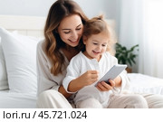 A joyful moment between a mother and her little daughter as they share laughter over a phone in their bright, cozy bedroom. Стоковое AI-изображение, AI-художник Sergey Grishin / Фотобанк Лори