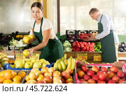 Girl seller of garden-stuff store works near showcase, sorting apples, checking goods. Стоковое фото, фотограф Яков Филимонов / Фотобанк Лори