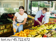 Young female customer made beeline for fresh produce section, pick juiciest oranges. Стоковое фото, фотограф Яков Филимонов / Фотобанк Лори