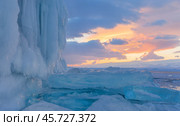 Winter landscape of frozen Baikal Lake at sunset. View of snowy hummocks with large fragments of transparent ice floes near icy rocks of Olkhon Island with ice crust on cold evening. Natural background. Стоковое фото, фотограф Виктория Катьянова / Фотобанк Лори