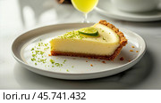 Slice of smooth key lime pie with a graham cracker crust, topped with lime zest and a lime slice, served on a white plate in soft lighting. Стоковое AI-изображение, AI-художник Башкирова Анна / Фотобанк Лори