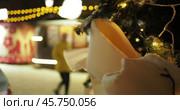 Holiday season. People are walking next to a Christmas tree and beautiful installations with iridescent multicolored lights against the background of a building with an illuminated facade. Hand held.  Siberia.  Out of focus. Стоковое видео, видеограф Сергей Медведев / Фотобанк Лори