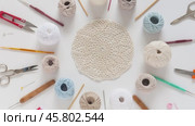 Video of needlework and crochet supplies lying around beautiful hand crocheted lace doily on white background. DIY concept. Crocheting as a hobby. Flat lay, close-up, mock up. Стоковое видео, видеограф Виктория Катьянова / Фотобанк Лори
