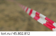 A close-up of a red and white striped tape, used for marking off areas, stretches into the blurred background. Usually such tape is used to cordon off areas. The wind ruffles the red and white ribbon. Стоковое видео, видеограф Воловодов Владимир / Фотобанк Лори
