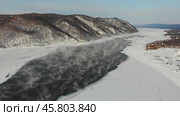 Aerial view of the ice-free source of the Angara River near Lake Baikal, surrounded by snow-capped hills. Mist and steam rise from the water. Стоковое видео, видеограф Виктория Тельминова / Фотобанк Лори