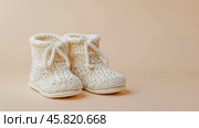 Close up of textile baby booties. Pregnancy concept, Pairs of baby shoes on a beige background. Gender neutral baby garment and accessories. Organic newborn bootie, fashion, branding. Gender neutral. Стоковое AI-видео, аниматор Марина Демидюк / Фотобанк Лори