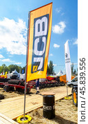 Dealership flag JCB against a blue sky. JCB is a British multinational manufacturer of equipment for construction, agriculture (2022 год). Редакционное фото, фотограф FotograFF / Фотобанк Лори