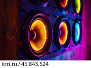 Colorful loudspeakers playing music with warm and vibrant backlight on wooden wall. Стоковое AI-изображение, AI-художник Иван Рябоконь / Фотобанк Лори