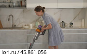 Smiling housewife in blue dress run vacuum cleaner floor covering near dining table. Стоковое видео, видеограф Яков Филимонов / Фотобанк Лори