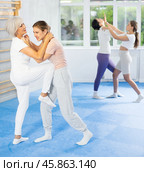 Senior woman performing head hold with knee strike to midsection in training sparring. Стоковое фото, фотограф Яков Филимонов / Фотобанк Лори