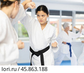 Asian female karateka engaging kumite with rival in training room. Стоковое фото, фотограф Яков Филимонов / Фотобанк Лори