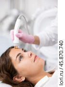 Unrecognizable beautician doctor doing RF lifting procedure for flawless woman face laying in beauty salon. Hardware cosmetology. Стоковое фото, фотограф Яков Филимонов / Фотобанк Лори