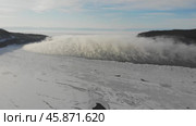 A serene winter view of the frozen Lake Baikal surrounded by mountains. Fog hovers over the unfrozen source of the Angara River. Стоковое видео, видеограф Виктория Тельминова / Фотобанк Лори