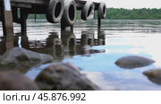 Dock with a tire on each side. The water is calm and the sky is blue. The dock is in a lake. Стоковое видео, видеограф Скрипачев Антон / Фотобанк Лори