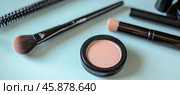 Makeup powder, brushes and applicators lying on light blue surface. Стоковое AI-изображение, AI-художник Юрий Поздников / Фотобанк Лори
