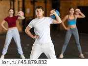 Guy in gym does exercises with kettlebell, lifts and lowers heavy kettlebell with one hand. Стоковое фото, фотограф Яков Филимонов / Фотобанк Лори