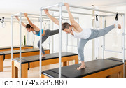 Focused man exercising on trapeze table at group Pilates class. Стоковое фото, фотограф Яков Филимонов / Фотобанк Лори