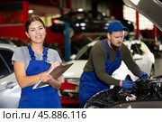 Female car service worker keeps records of work performed by auto mechanics in car service station - makes notes on paper. Стоковое фото, фотограф Яков Филимонов / Фотобанк Лори