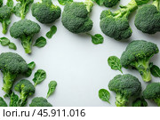 Fresh broccoli florets and green leaves laid out on a light background. The bright green color of the vegetables creates a contrast with the white surface, emphasizing their freshness and texture. The broccoli florets have a dense structure with small tubercles, characteristic of this vegetable. The leaves look juicy, with soft veins, adding naturalness to the composition. The arrangement of the elements is symmetrical, leaving the center of the image empty, which makes the frame minimalistic and aesthetically pleasing. This image can be associated with healthy eating and naturalness. Стоковое AI-изображение, AI-художник Анна Кривицкая / Фотобанк Лори
