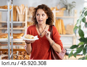 Happy female customer tries delicious bocadillo in bakery interior. Стоковое фото, фотограф Яков Филимонов / Фотобанк Лори