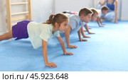 Group of little children doing push-ups on sports mats during a self-defense class in a gym. Стоковое видео, видеограф Яков Филимонов / Фотобанк Лори