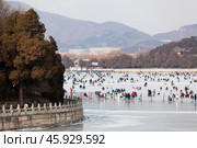 Катание на коньках в выходной день на озере Kunming Lake у Летнего дворца. Вид на остров Nanhu. Пекин, Китай (2024 год). Редакционное фото, фотограф Кекяляйнен Андрей / Фотобанк Лори