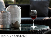 A glass of red alcoholic drink or wine on a glass table on the veranda. The concept of alcoholism, a party, or a holiday. Стоковое фото, фотограф Photojuli / Фотобанк Лори