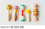Set of five colorful wooden and fabric baby rattles in different designs and patterns on a white background. Early learning toys for sensory play. Стоковое AI-изображение, AI-художник Екатерина Каболова / Фотобанк Лори