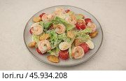 Caesar salad with tiger prawns, cherry tomatoes, croutons, parmesan cheese, quail eggs and romaine lettuce. A woman adds cheese to a plate. Traditional American dish. Close-up, selective focus. Стоковое видео, видеограф Наталья Любина / Фотобанк Лори