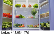 Refrigerator door opening to reveal an abundance of fresh food options. Стоковое видео, видеограф Данил Руденко / Фотобанк Лори