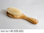 Wooden bath brush with natural bristles lying on white background. Стоковое AI-изображение, AI-художник Иван Рябоконь / Фотобанк Лори