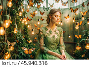Portrait of a beautiful girl in a green dress among many suspended light bulbs and butterflies fluttering around her. Daydreaming. A magical atmosphere. Стоковое AI-изображение, AI-художник Photojuli / Фотобанк Лори