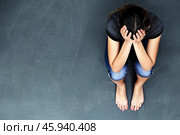 An overhead view of a woman sitting on a concrete floor, conveying feelings of distress, sadness, and anxiety. Copy space. Стоковое AI-изображение, AI-художник Михаил Строгалев / Фотобанк Лори