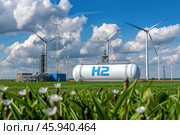 Hydrogen storage tanks marked with H2 and wind turbines stand in a green, eco-friendly landscape, under a bright sky. Стоковое AI-изображение, AI-художник Михаил Строгалев / Фотобанк Лори