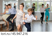 Teen girl in elegant evening dress dances incendiary twist with boy partner during choreography lesson. Стоковое фото, фотограф Яков Филимонов / Фотобанк Лори
