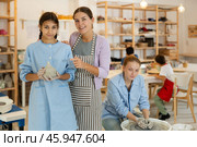 Preteen girl holding clay jug is standing in workroom with teacher. Стоковое фото, фотограф Яков Филимонов / Фотобанк Лори