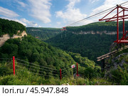 Zipline attraction through the Mishoko River Canyon in the Caucasus Mountains in the Mishoko Extreme Park on a sunny summer day, Kamennomostsky village, Republic of Adygea, Russia. Стоковое фото, фотограф Ula Ulachka / Фотобанк Лори