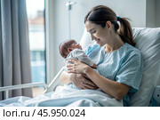 A woman in a hospital bed in the maternity ward. Mom has a newborn baby in her arms. Pregnancy and childbirth. Стоковое AI-изображение, AI-художник Photojuli / Фотобанк Лори
