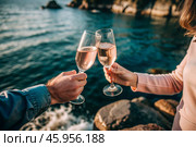 Glasses of pink sparkling wine in the hands of a couple in love. People on a romantic date. The concept of love. Стоковое AI-изображение, AI-художник Photojuli / Фотобанк Лори
