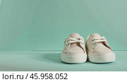 Close up of textile baby booties. Pregnancy concept, Pairs of baby shoes on a green background. Gender neutral baby garment and accessories. Organic newborn bootie, fashion, branding. Gender neutral. Стоковое AI-видео, аниматор Марина Демидюк / Фотобанк Лори