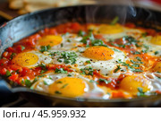 Eggs poached in tomato sauce with fresh herbs simmering in cast iron skillet. Стоковое AI-изображение, AI-художник Иван Рябоконь / Фотобанк Лори
