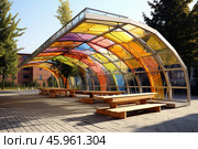 Modern picnic area covered by colorful polycarbonate roof providing shade. Стоковое AI-изображение, AI-художник Иван Рябоконь / Фотобанк Лори