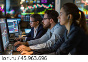 Employees monitoring financial data in a trading room while analyzing market trends during the workday at an investment firm. Стоковое AI-изображение, AI-художник Sergey Grishin / Фотобанк Лори
