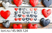 Collection of red and black hearts is artfully arranged on a rustic wooden surface, showcasing love's vibrant colors for Valentine's Day. The display invites feelings of romance and affection. Greeting card design. Стоковое AI-изображение, AI-художник Юлия Ильина / Фотобанк Лори