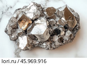 A mineral with characteristic metallic crystals. This is pyrophyllite, which has a bright metallic luster that creates a beautiful reflection of light. It consists of large multifaceted crystals with angular surfaces and a shiny texture. Some areas of the mineral have golden hues, which creates a contrast with the silvery and gray areas of the crystals. The crystals are arranged in groups, creating the effect of a dense accumulation of the mineral. The background emphasizes the beauty of the mineral, highlighting it in the center of the composition. Стоковое AI-изображение, AI-художник Анна Кривицкая / Фотобанк Лори