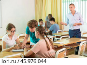 Teen girls and boys solving teacher assignments in small groups. Стоковое фото, фотограф Яков Филимонов / Фотобанк Лори
