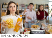Daughter chose sweet drink and potato chips in store, and quarrels with parents over choice of food. Стоковое фото, фотограф Яков Филимонов / Фотобанк Лори