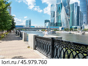 Набережная Тараса Шевченко, мост Багратион, небоскребы Москва-сити и сидящая на парапете девушка летним днем (2021 год). Редакционное фото, фотограф Лариса Гордеева / Фотобанк Лори