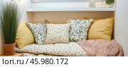 Cozy reading nook with decorative pillows and knitted blanket inviting relaxation. Стоковое AI-изображение, AI-художник Юрий Поздников / Фотобанк Лори