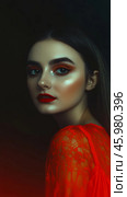 Close-up of a woman with bold red lipstick and a mischievous smirk in dramatic lighting against a dark background. Стоковое AI-изображение, AI-художник 123 12 / Фотобанк Лори